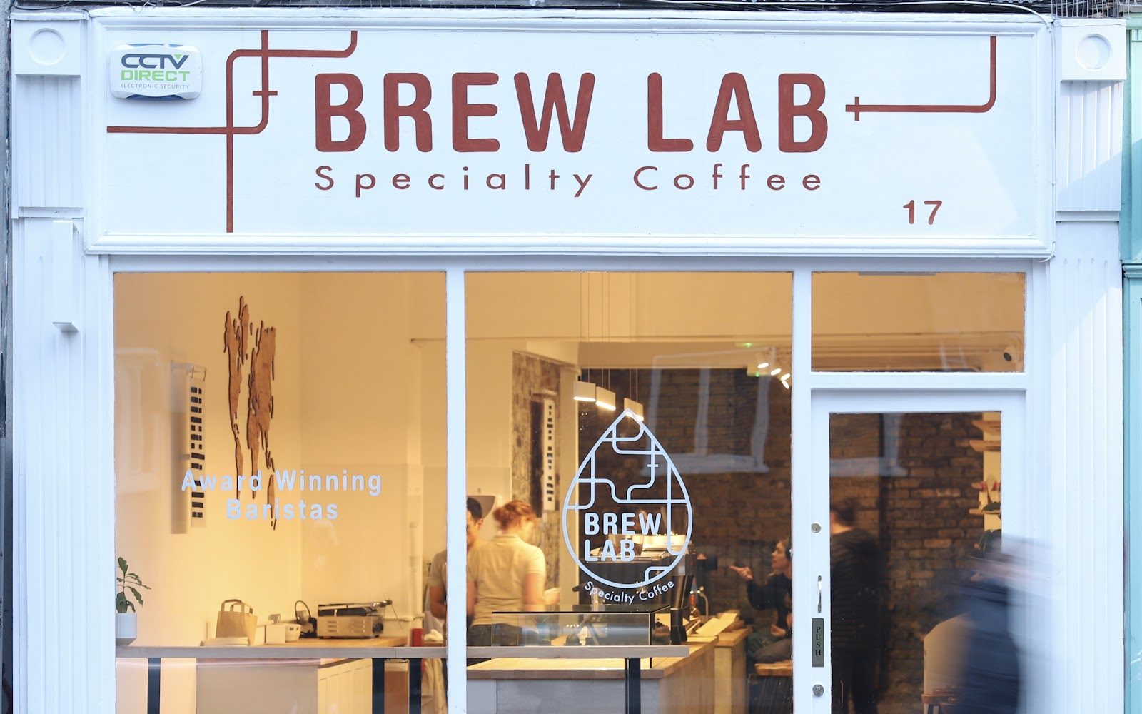 Brew Lab's white shopfront on Redmond's Hill, with rust lettering reading Brew Lab Specialty Coffee and a window decal for Award Winning Baristas